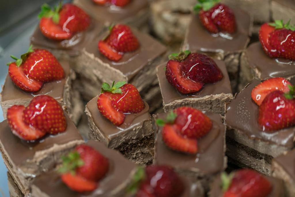 Šokolādes kūkas gabali ar svaigām zemenēm uz virsmas, kas piešķir krāsainu un gardu izskatu. Ideāli piemēroti desertiem vai svinībām.