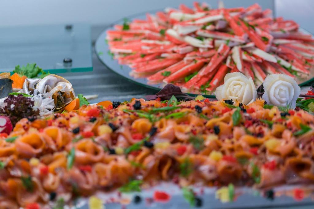 Svaigu jūras produktu un makaronu uzkodu galds, dekorēts ar dārzeņiem un ēstgribu rosinošām ziedu kompozīcijām. Ideāls veselīgu un krāsainu ēdienu paraugs.