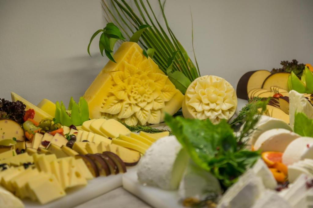 Siera galds ar dažādām siera šķirnēm un dekoratīviem dārzeņiem, izceļot mākslinieciskas siera figūras. Ideāli piemērots svinībām un gardēžu pasākumiem.