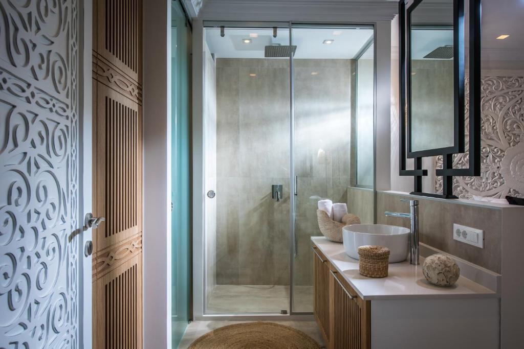 Mūsdienīga vannas istaba ar stikla dušu, elegantu izskatu un dabīgām krāsām. Svaigs un tīrs dizains, kas ietver arī koka elementus un tekstili.