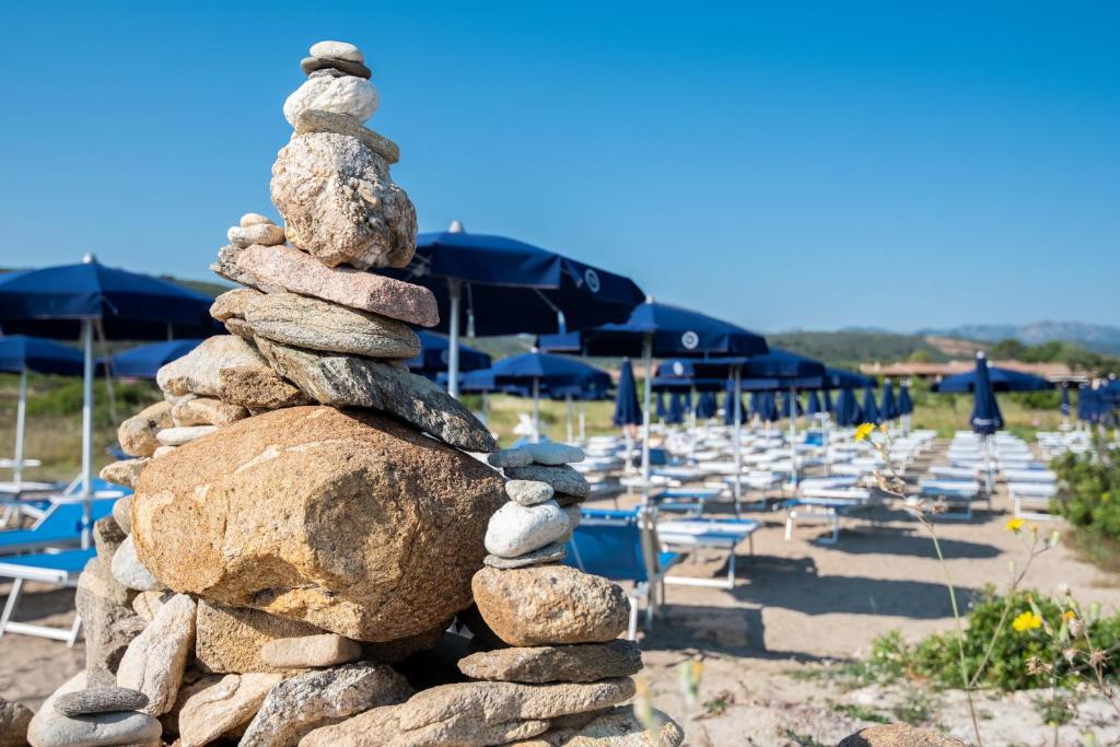 Akmeņu kompozīcija pludmalē ar saules parkiem fona. Ideāls skats uz relaksāciju un dabu.