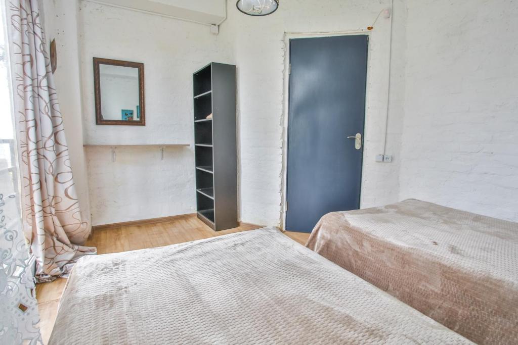 Gaisma un moderns istabas interjers ar divām gultām, melnu plauktu un spoguli uz baltas ķieģeļu sienas. Pieejams melns durvju tonis un koka grīdas segums.