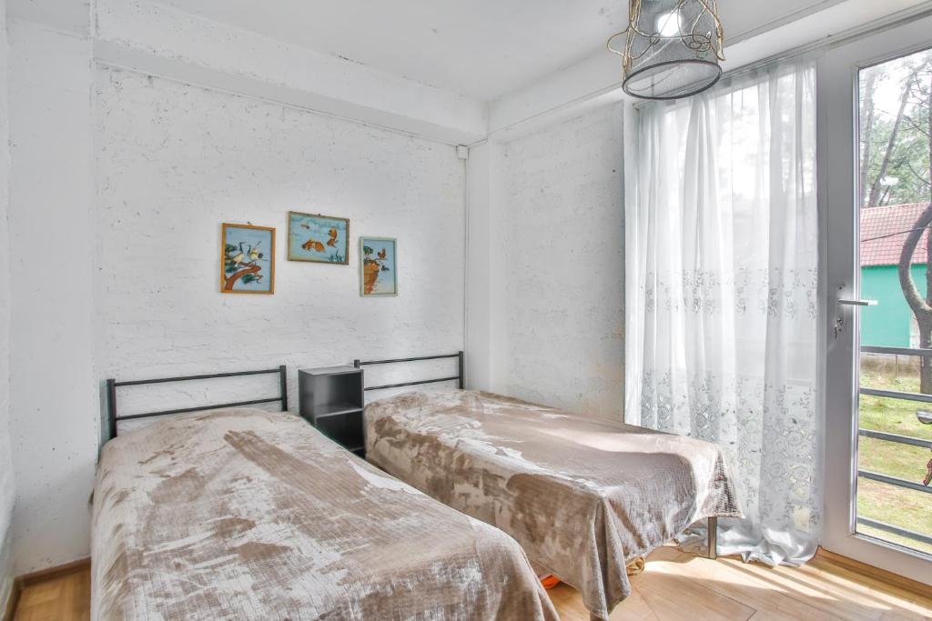 Gaisma un mūsdienīga guļamistaba ar divām atsevišķām gultām, dekorēta ar mākslas darbiem un lieliem logiem, kas nodrošina dabīgu apgaismojumu.