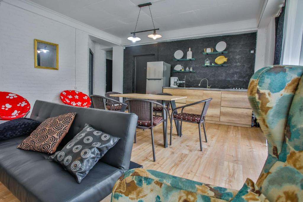 Moderns viesistabas un virtuves interjers ar sarkanām krēsliem un koka mēbelēm. Gaismas un krāsas rada mājīgu atmosfēru.