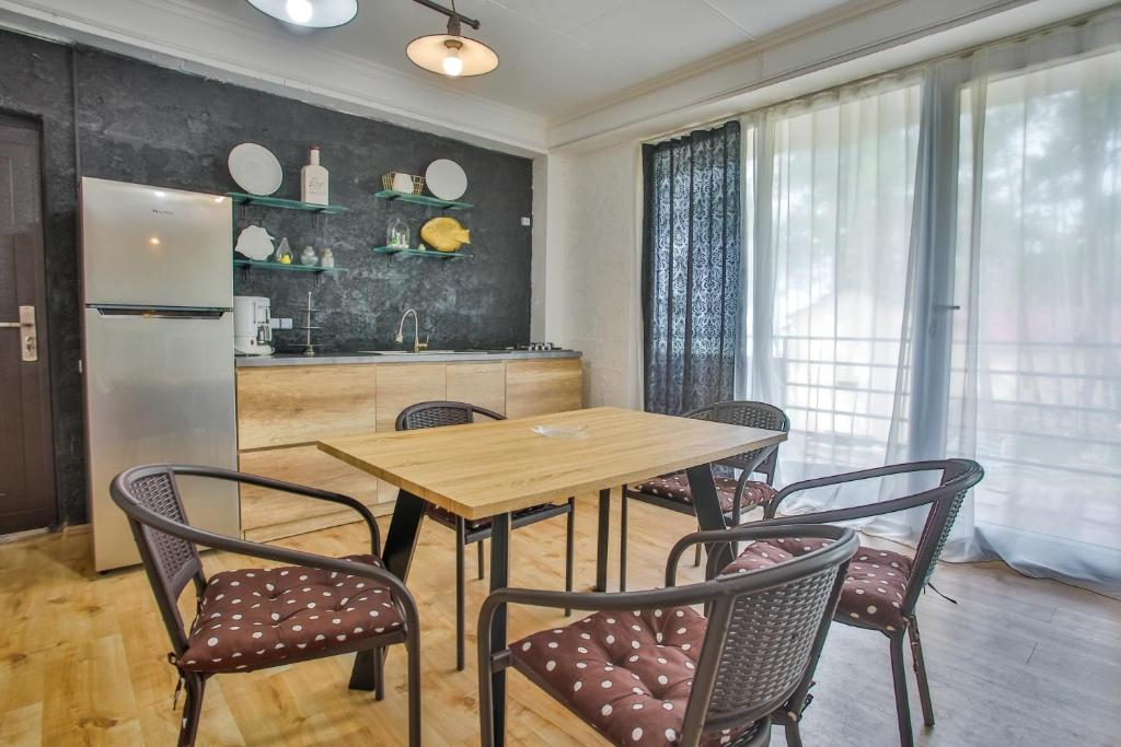 Modernā virtuve ar koka galdu un ērtām krēsliem, izgaismota ar dabisko gaismu. Sienas dekorētas ar plauktiem un mākslinieciskām detaļām.