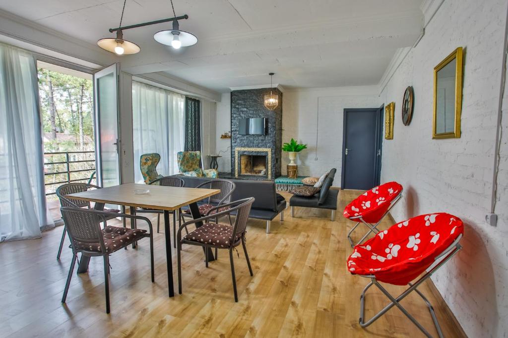 Mūsdienīgs viesistaba ar ēdamgaldu, krēsliem un kamīnu, kas piedāvā mājīgu atmosfēru un dabīgu apgaismojumu. Logi ļauj ieplūst gaismai un nodrošina skatu uz dabu.