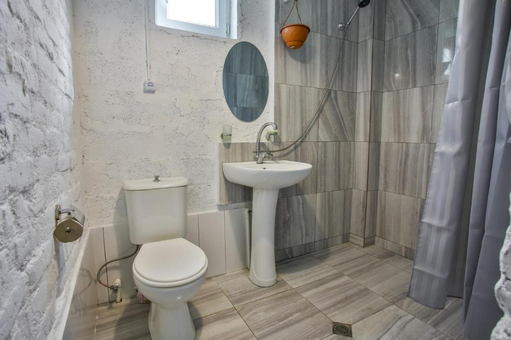 Moderns vannas istabas interjers ar dušu, tualeti un izlietni. Gaišas flīzes un gaiša apdare rada svaigu un tīru atmosfēru.