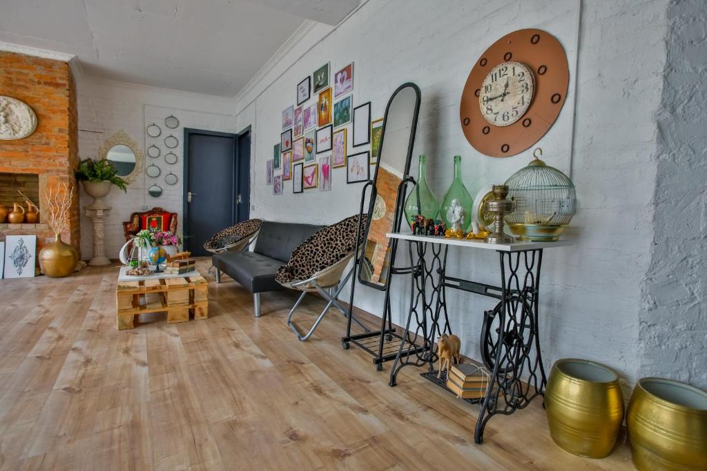 Mūsdienīgs viesistabas interjers ar koka grīdu, dekoratīvām gleznām uz sienām un stilīgu mēbeļu kombināciju, tostarp dīvānu un galdu no koka paletēm. Interjers ir papildināts ar dažādiem dekoratīviem elementiem, piemēram, spoguļiem un puķēm.