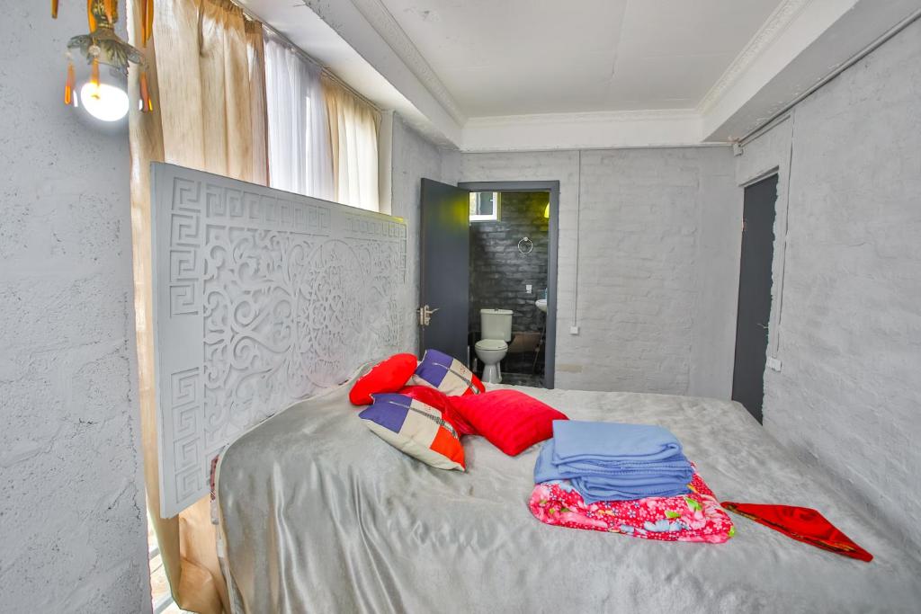 Mūsdienīga guļamistaba ar dekoratīvu gultas atzveltni, spilveniem un gultas veļu, kas izceļas ar krāsainām akcentiem. Telpā ir gaišas, dabīgas gaismas un piekļuve vannas istabai.