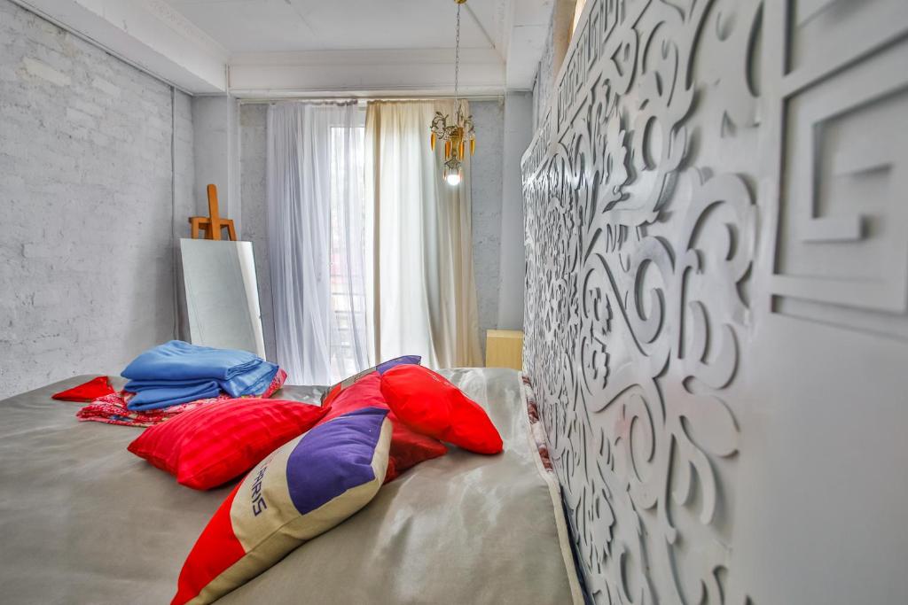 Gultas telpa ar dekoratīviem spilveniem, gaišām aizkariem un mākslas elementiem. Svarīgs interjera akcentu uzsvars uz komfortu un stilu.