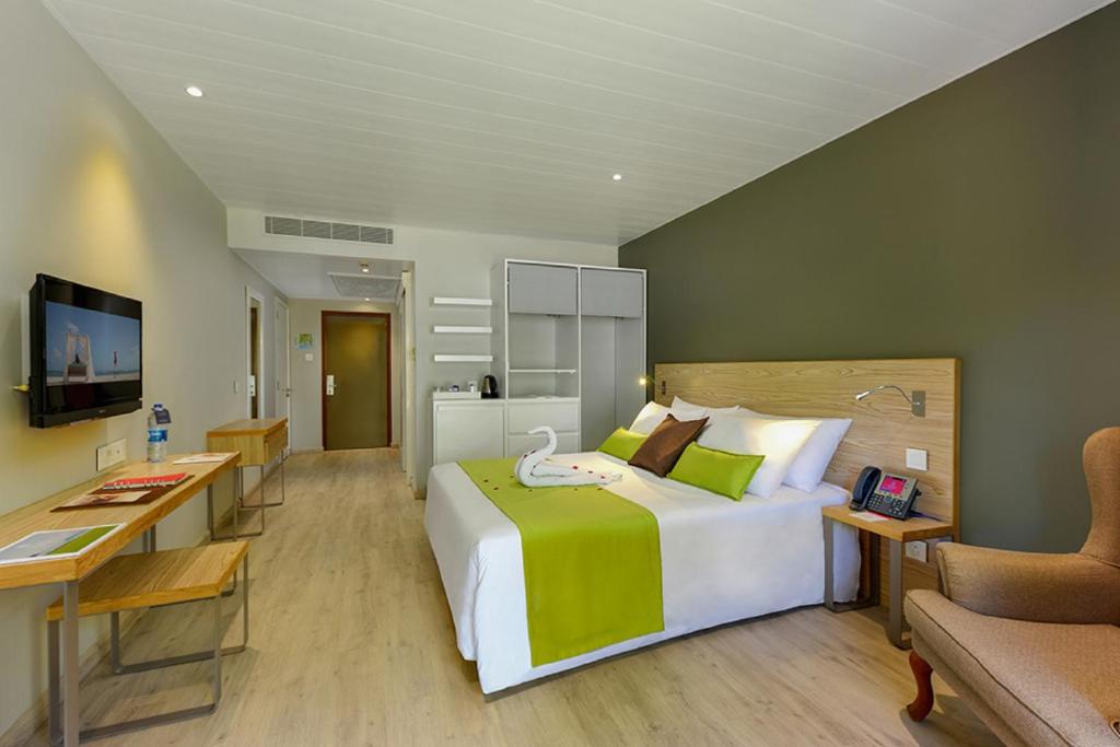 Mūsdienīga viesnīcas numura interjers ar gultu, koka mēbelēm un televizoru. Numurā ir arī datora galdiņš un krēsls, kā arī skapji un mini ledusskapis.