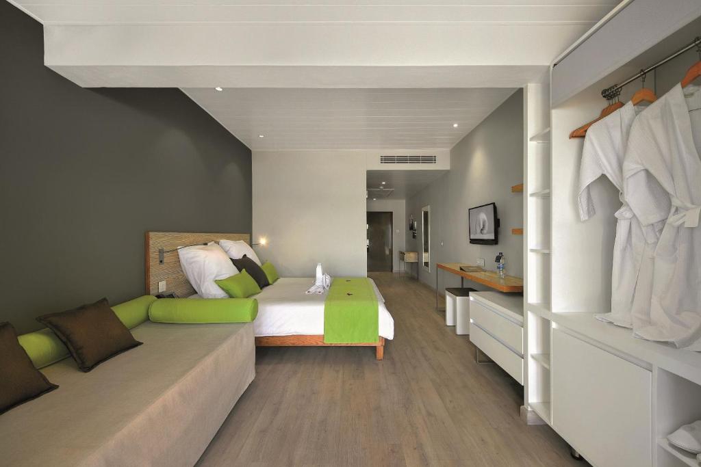 Mūsdienīgs viesnīcas numurs ar ērtu gultu, dīvānu un zaļu dekora akcentu. Interjers ir gaišs un elegants, radot relaksējošu atmosfēru.