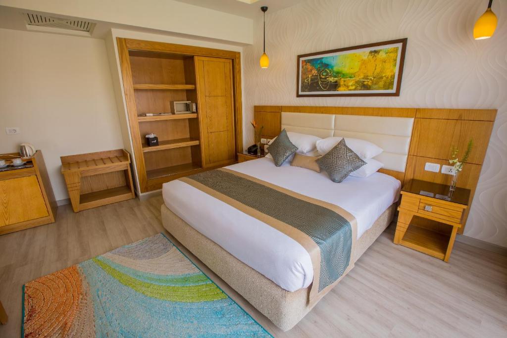 Mūsdienīgs viesnīcas numurs ar plašu gultu, elegantu dekoru un koka mēbelēm. Telpā ir arī plaukti un televizors, radot komfortablu atmosfēru.