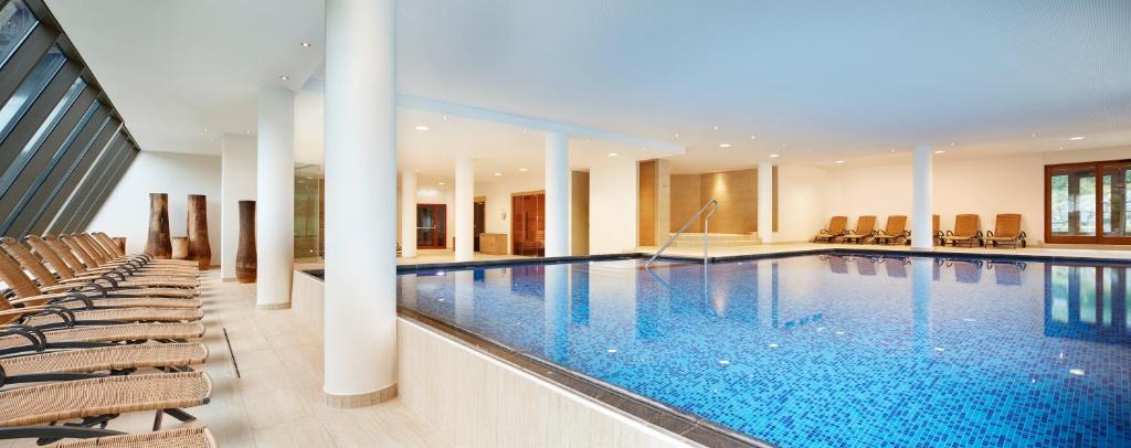 Moderns iekštelpu baseins ar zilām flīzēm un ērtām atpūtas krēslām, kas izvietoti gar baseinu. Gaisīga un plaša telpa ar lieliem logiem, kas nodrošina dabīgu apgaismojumu.