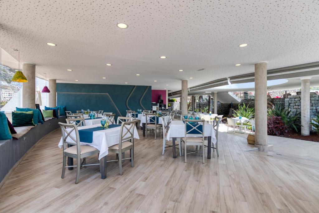 Mūsdienīgs restorāns ar elegantiem galdiem un krāsainām dekorācijām, nodrošinot patīkamu atmosfēru. Telpai raksturīga gaiša apgaismojuma un stilīga interjera kombinācija.