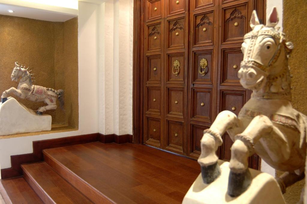 Ieejas interjers ar koka durvīm un dekoratīviem zirgveida skulptūrām, kas piešķir telpai elegantu un mājīgu atmosfēru.