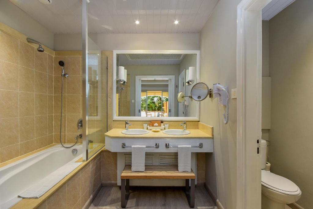 Mūsdienīgs vannas istabas interjers ar vannu, dušu un divām izlietnēm. Gaisma un spoguļi rada plašuma sajūtu.