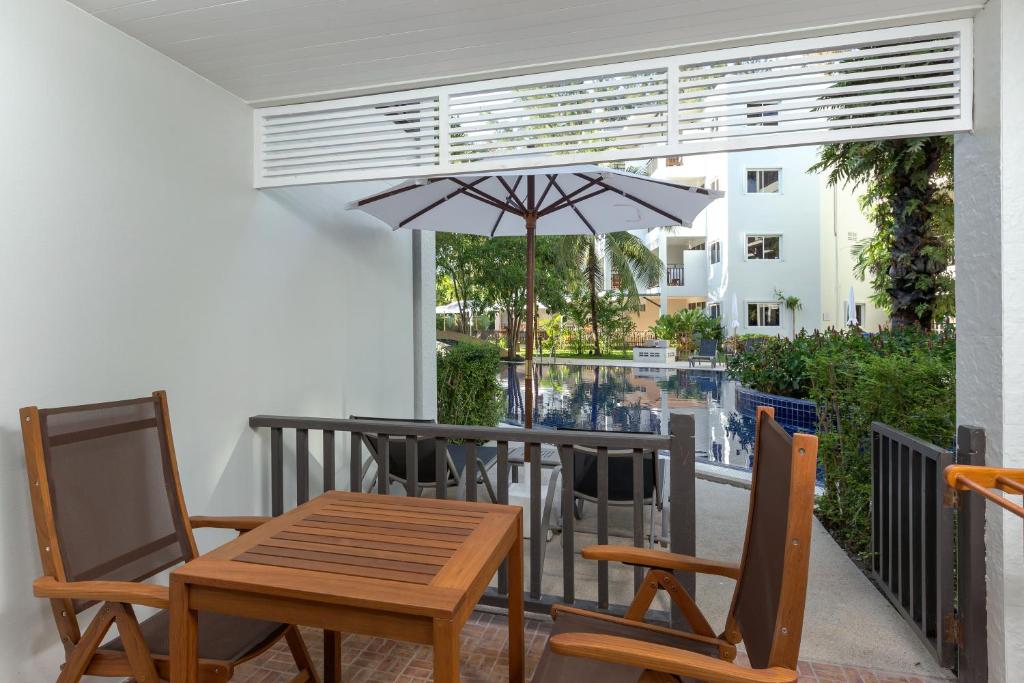 Terase ar koka galdu un krēsliem, kas skatās uz baseinu, kurā redzami zaļumi un palmas. Ideāla vieta relaksācijai un atpūtai.