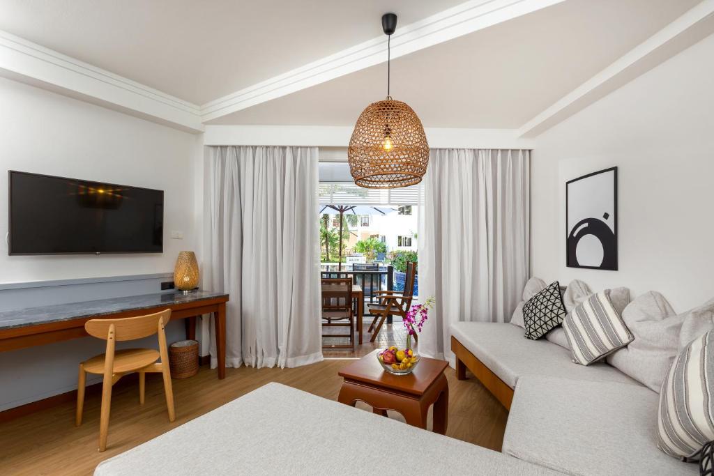 Mūsdienīgs viesnīcas numurs ar gaišām krāsām, ērtu dīvānu un koka mēbelēm, kā arī lielu logu, kas ved uz terasi. Interjerā ir pieejama televizors un dekoratīvas detaļas, radot viesmīlīgu atmosfēru.