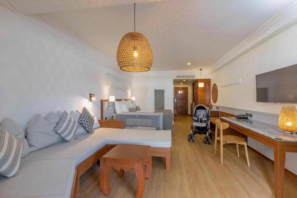 Mūsdienīgs viesnīcas numurs ar gaišu interjeru, ērtu dīvānu, bērnu ratiņiem un darba galdu. Gaismas elementi un koka akcenti piešķir telpai siltu atmosfēru.