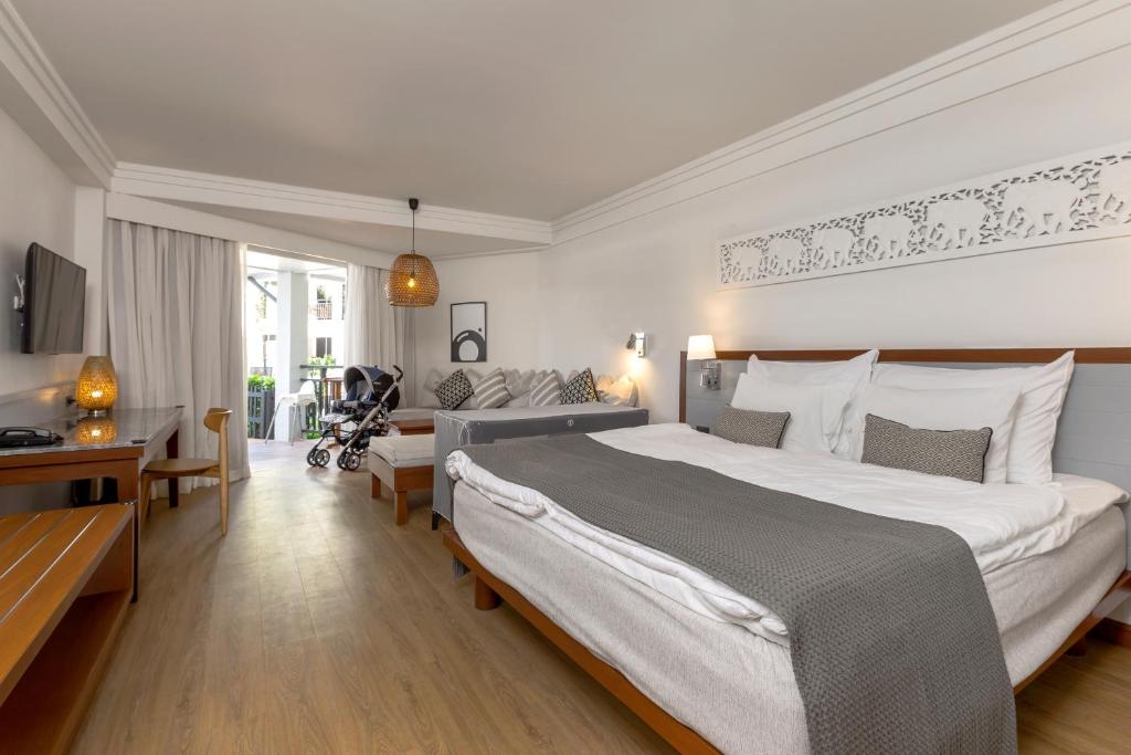 Mūsdienīgs viesnīcas numurs ar plašu gultu, dīvānu un balkonu. Istabā ir televizors, rakstāmgalds un bērnu ratiņi, kas piešķir mājīgu atmosfēru.