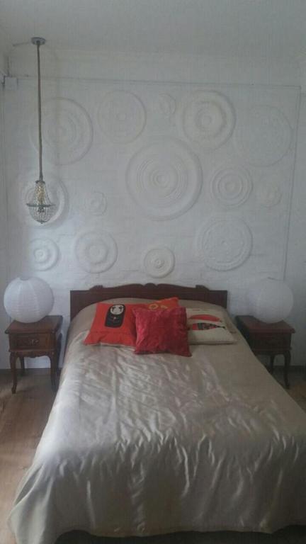 Gultas telpa ar modernu dekoru un spilveniem. Sienas apdare ar spirālveida reljefiem, apkārt gultai ir divas stilīgas lampas.