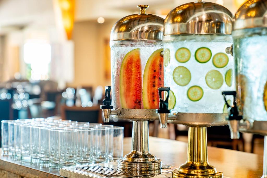 Dzeramā ūdens izsniegšanas stacija ar svaigiem augļiem, piemēram, arbūziem un citrona šķēlītēm, kā arī glāzēm, kas ir gatavas pasniegšanai.