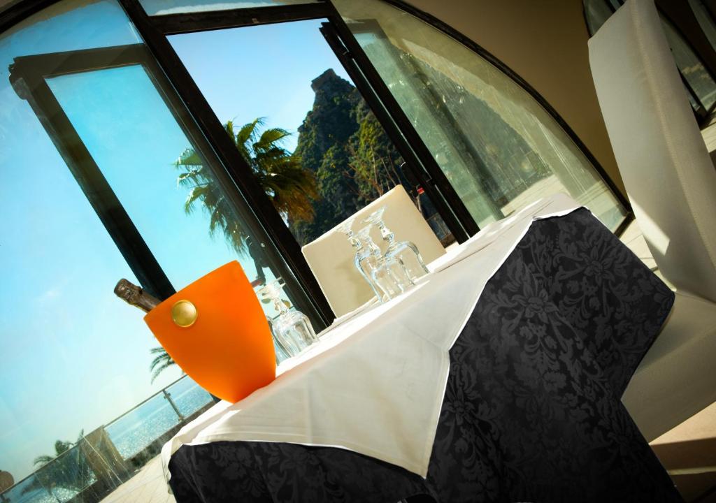 Elegantā pusdienu galda dekorācija ar dzirkstošo vīnu, ko ieskauj gleznains skats uz dabu. Svaigs un moderns restorāna interjers.