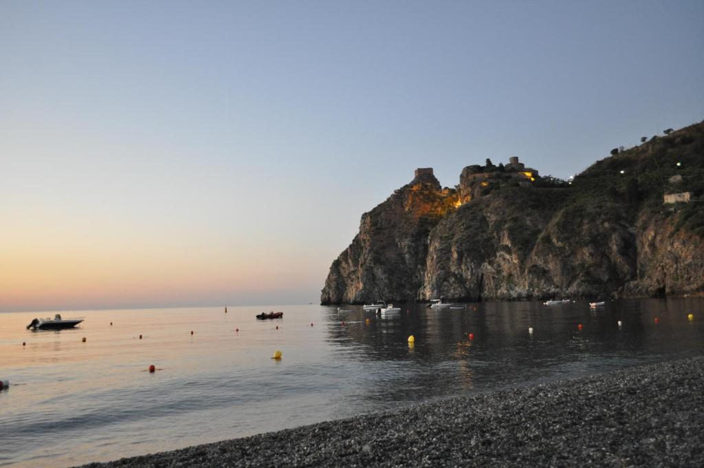 Jūras ainava ar klintīm un laivām saulrieta gaismā, radot mierīgu un gleznainu atmosfēru.