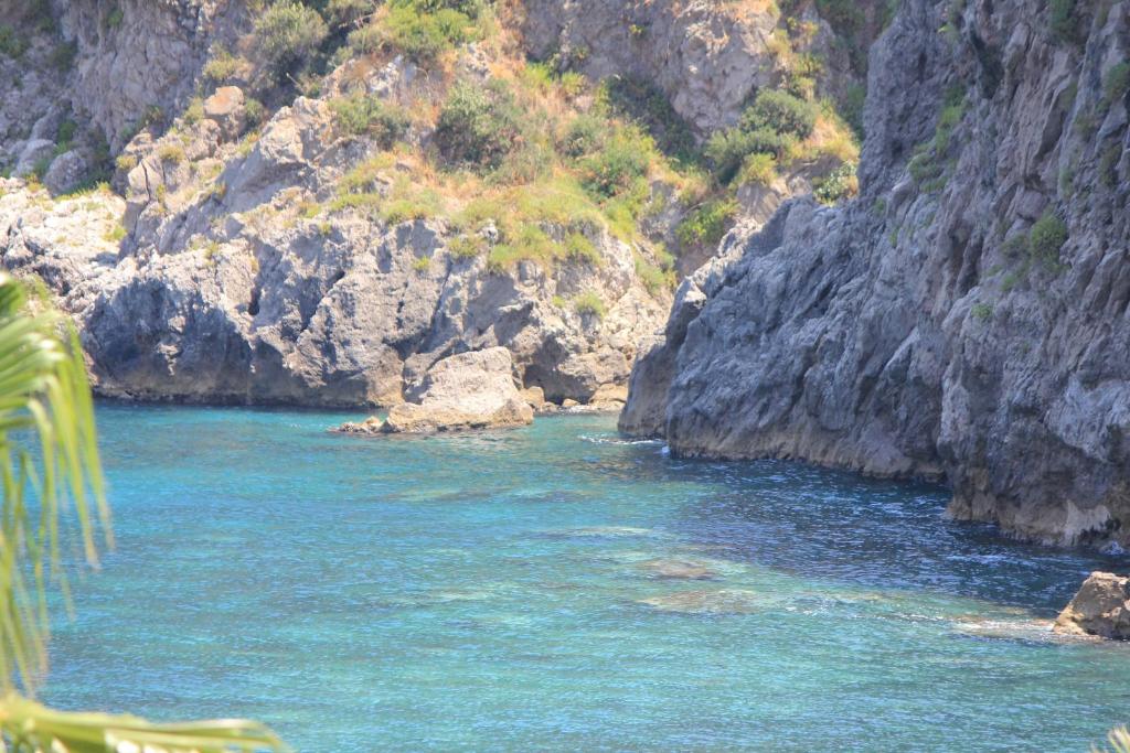 Skaista piekrastes ainava ar kristāldzidru ūdeni un klintīm, kas apņem pludmali. Dabas krāsu harmonija rada mierīgu un relaksējošu atmosfēru.