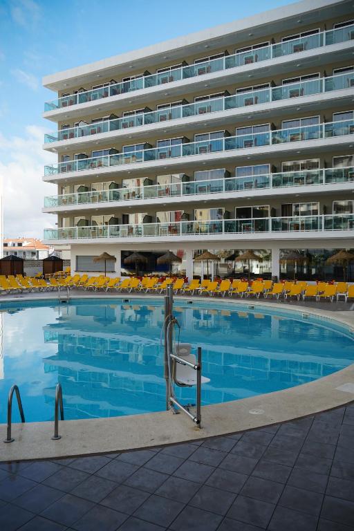 Moderns viesnīcas komplekss ar lielu peldbaseinu un saulessargiem. Viesnīca ir daudzstāvu ar balkoniem, kas piedāvā skatu uz ūdeni.