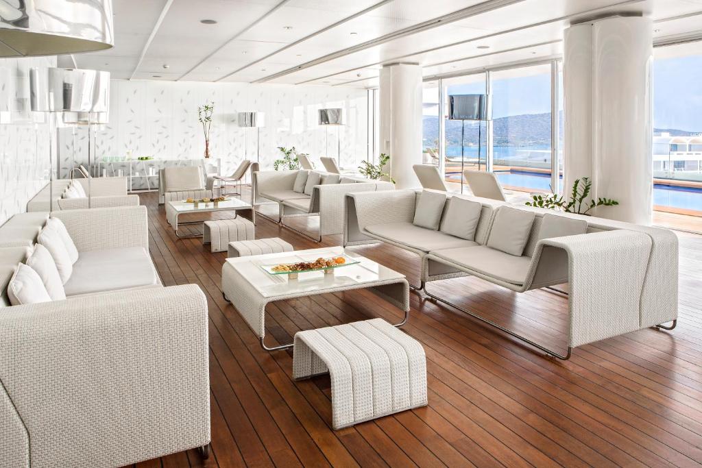 Moderna atpūtas telpa ar gaišiem dīvāniem un koka grīdu, kas piedāvā elegantus interjera risinājumus un skatu uz ūdeni. Ideāli piemērota relaksācijai un sociālām aktivitātēm.