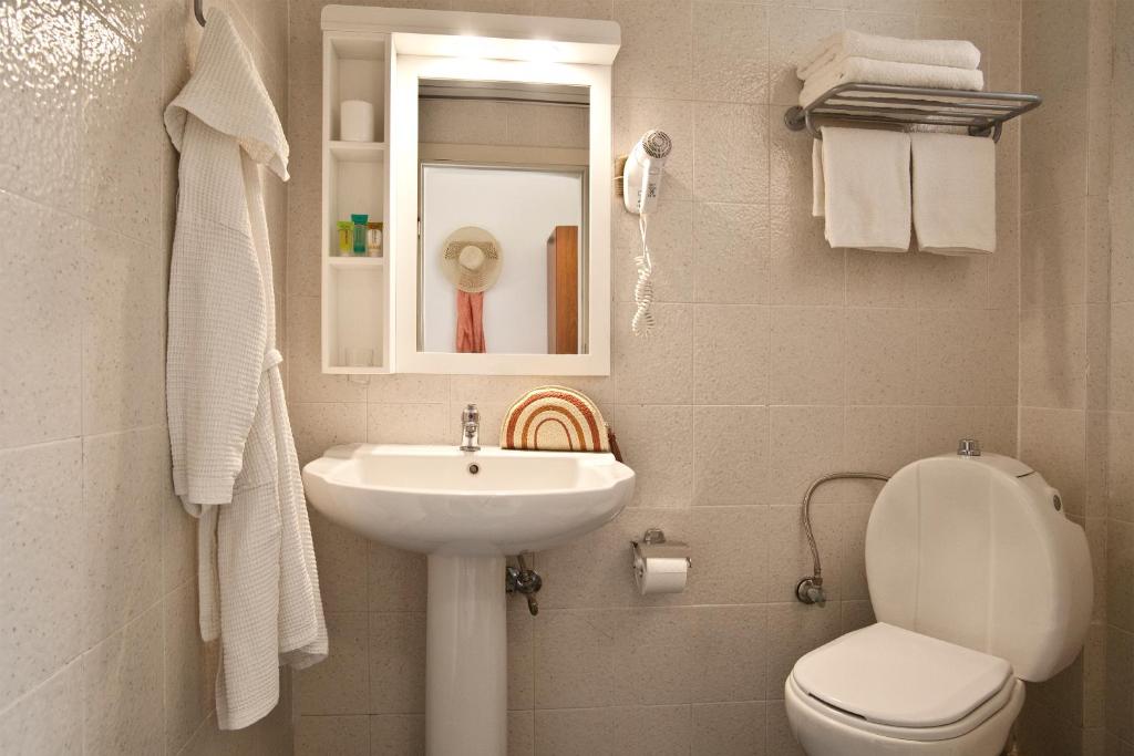 Moderns vannas istabas interjers ar izsmalcinātu izkārtojumu, kurā ir izlietne, tualete un spogulis, kā arī aksesuāri, piemēram, dvieļi un matu žāvētājs.