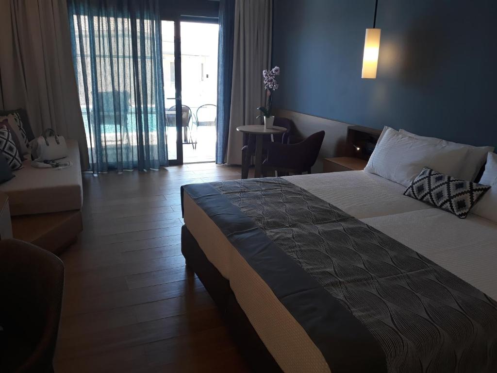 Mūsdienīgs viesnīcas numurs ar divām gultām, dīvānu un galdu, caur caurspīdīgām aizkariem redzama āra terase. Numurā ir gaiša krāsu palete un koka grīda.