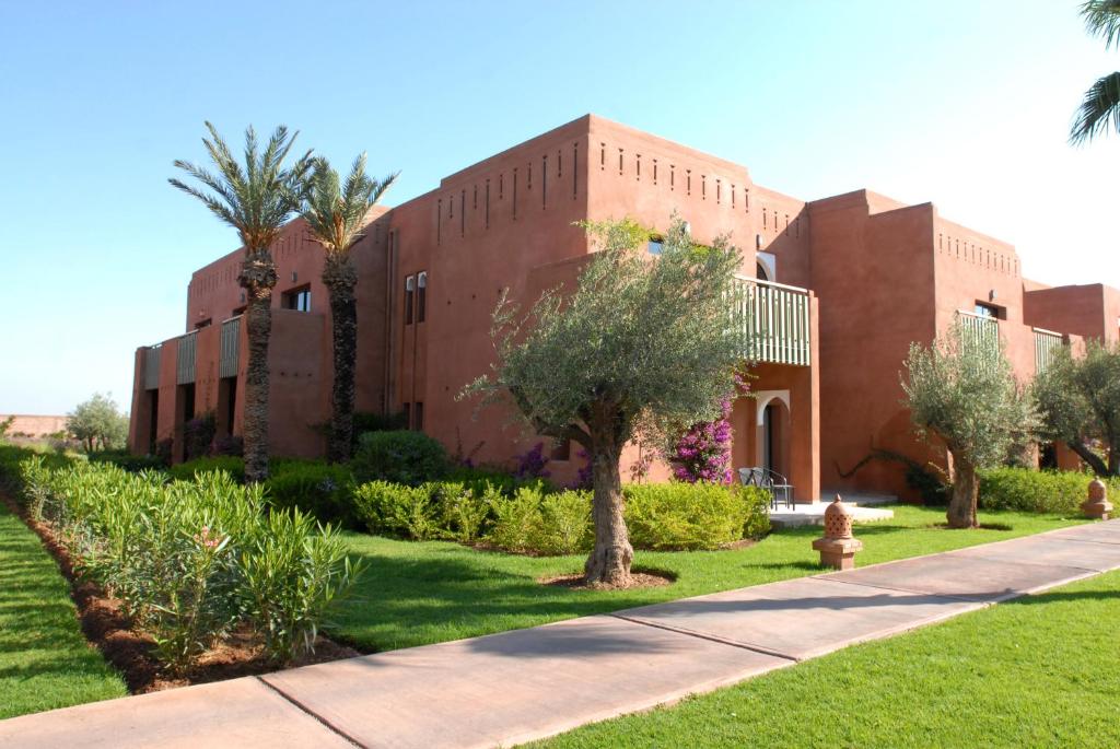 Mūsdienīga ēka ar sarkanu apdari, ieskauta zaļā dārzā ar palmu un olīvkoku stādiem. Ideāla vieta atpūtai un relaksācijai.