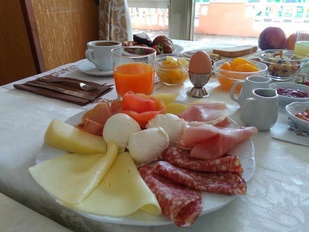 Brokastu galds ar dažādām delikatesēm, ieskaitot sieru, gaļu, augļus un dzērienus. Ideāls veids, kā sākt dienu.