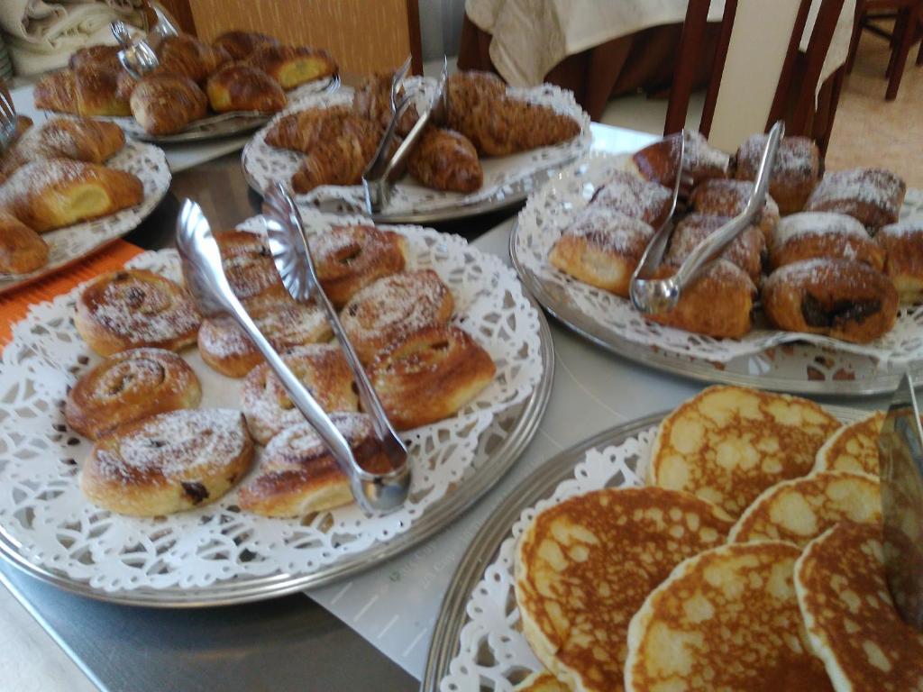 Saldumu galda klāšana ar dažādiem konditorejas izstrādājumiem, tostarp cepumiem, kruasāniem un pankūkām, rotātām ar pūdercukuru.