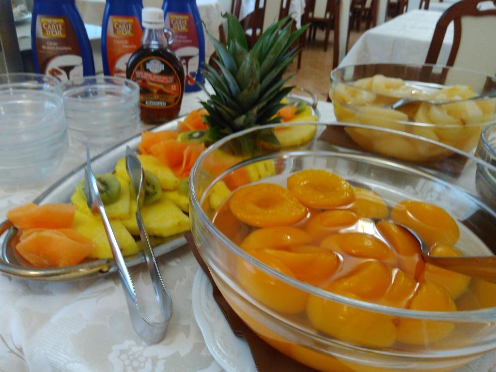 Svaigu augļu un konservētu persiku salāti uz galda, kopā ar sīrupiem un traukiem. Ideāli piemērots brokastīm vai desertam.