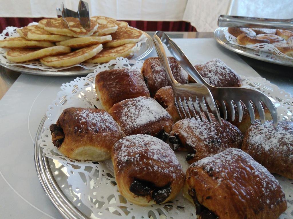 Garšīgu konditoreju šķīvji ar saldām bulciņām un pankūkām, rotāti ar pūdercukuru. Ideāls brokastu vai uzkodu variants.