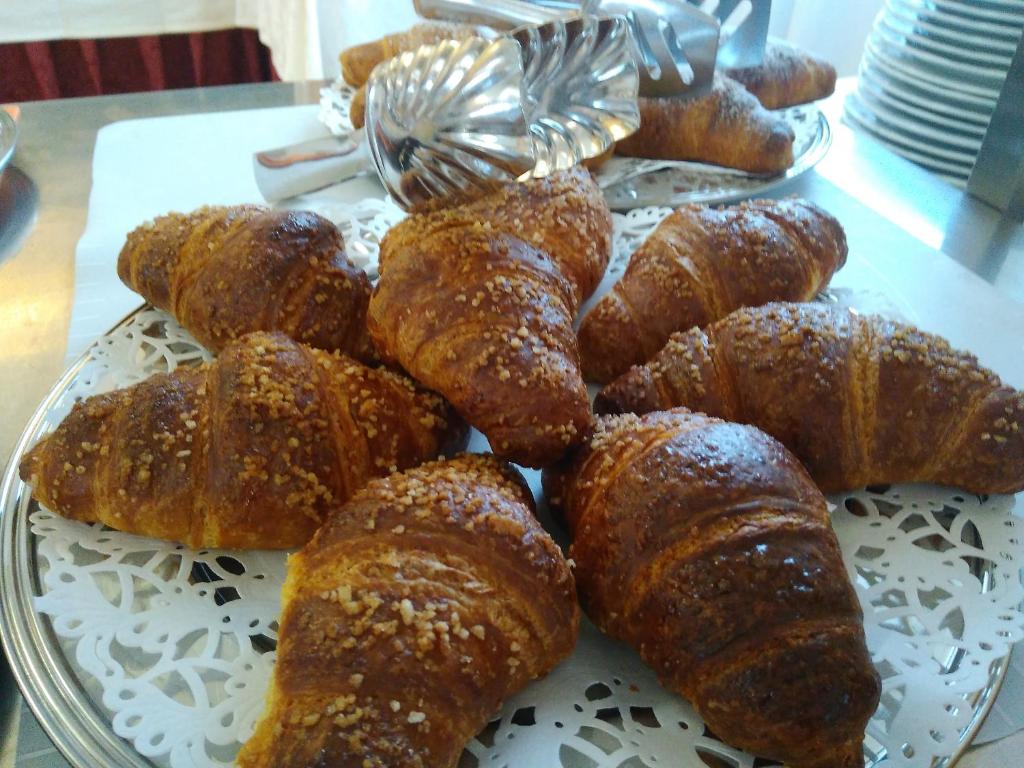 Saldie kruasāni ar kraukšķīgu virsu, izkārtoti uz dekoratīvas šķīvja. Šie gardie konditorejas izstrādājumi ir ideāli piemēroti brokastīm vai uzkodām.