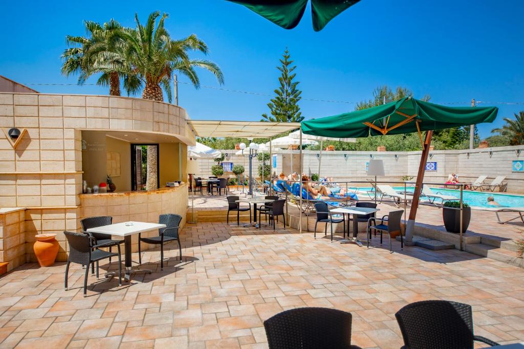 Atpūtas zona ar peldbaseinu, saules krēsliem un kafejnīcu, kur viesi bauda saulainu laiku un palmām ieskautu atmosfēru. Ideāla vieta relaksācijai un atpūtai.