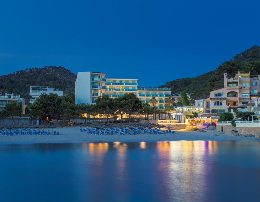 Jūras krasts ar viesnīcām un pludmales krēsliem, apgaismots tumsā.