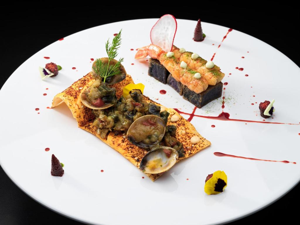 Mūsdienīgs gastronomisks ēdiens, kas sastāv no rīsu plāksnītes ar jūras veltēm un garnelēm, dekorēts ar ēdamām ziedlapiņām un krāsainiem mērķiem.