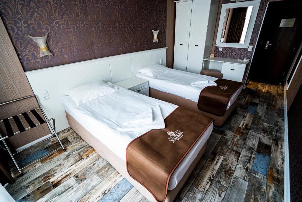 Mūsdienīgs viesnīcas numurs ar divām vienguļamajām gultām, dekorēts ar tumši brūnu un zeltītu tapeti. Interjers ietver koka grīdas un stilīgu mēbeļu komplektu.