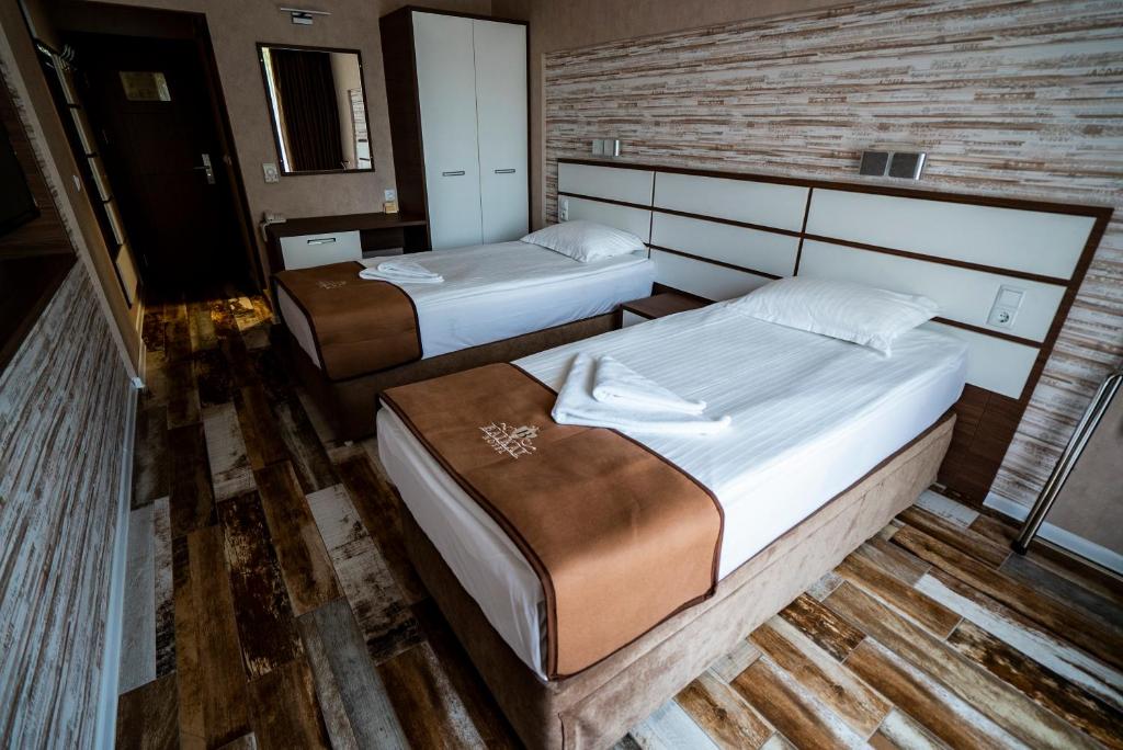 Mūsdienīga viesnīcas numura iekārtojums ar divām gultām, modernu dizainu un koka grīdu. Telpa ir gaiša un gaumīga, ar atsevišķu garderobi un spoguli.