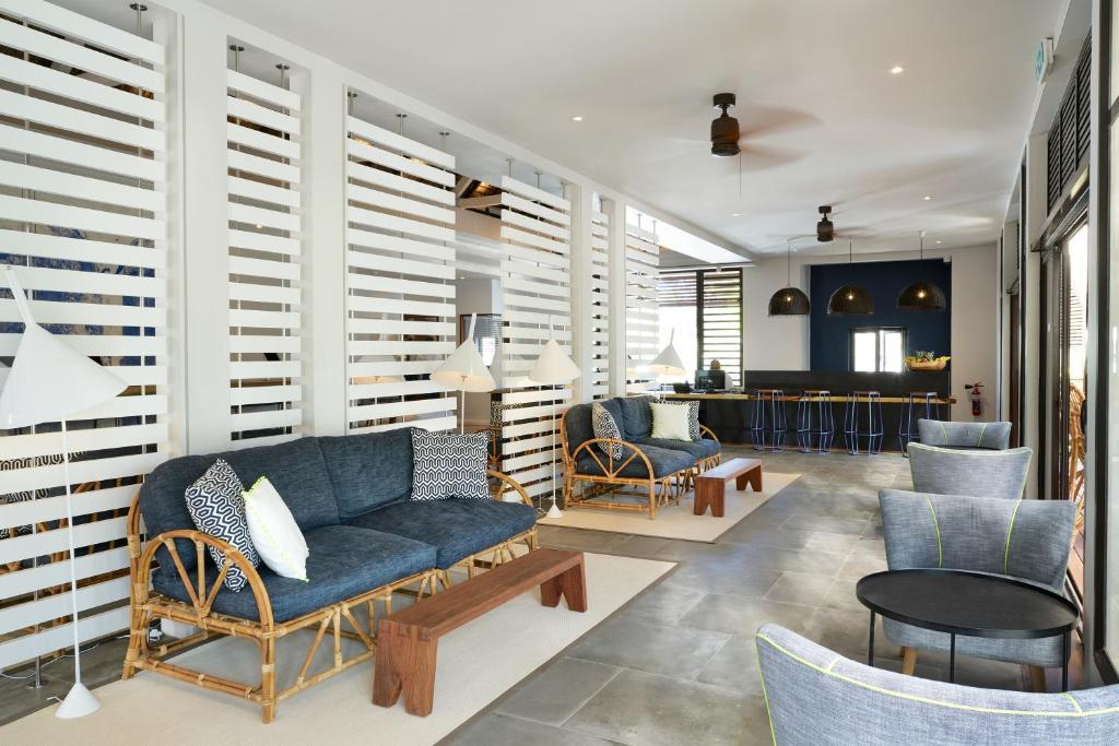 Mūsdienīgs viesnīcas interjers ar ratanām mēbelēm, gaišām krāsām un stilīgām lampām, radot relaksējošu un viesmīlīgu atmosfēru.