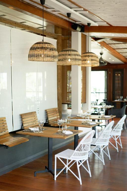 Mūsdienīga restorāna interjers ar koka mēbelēm un stilīgām grozāmo lampu gaismām, radot siltu un viesmīlīgu atmosfēru.