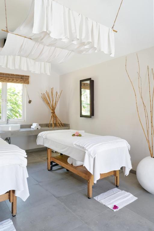 Mūsdienīga spa istaba ar divām masāžas galdiem, baltām drānām un mierīgu atmosfēru, kas veicina relaksāciju. Interjerā ir dabīgi elementi un gaišas krāsas.