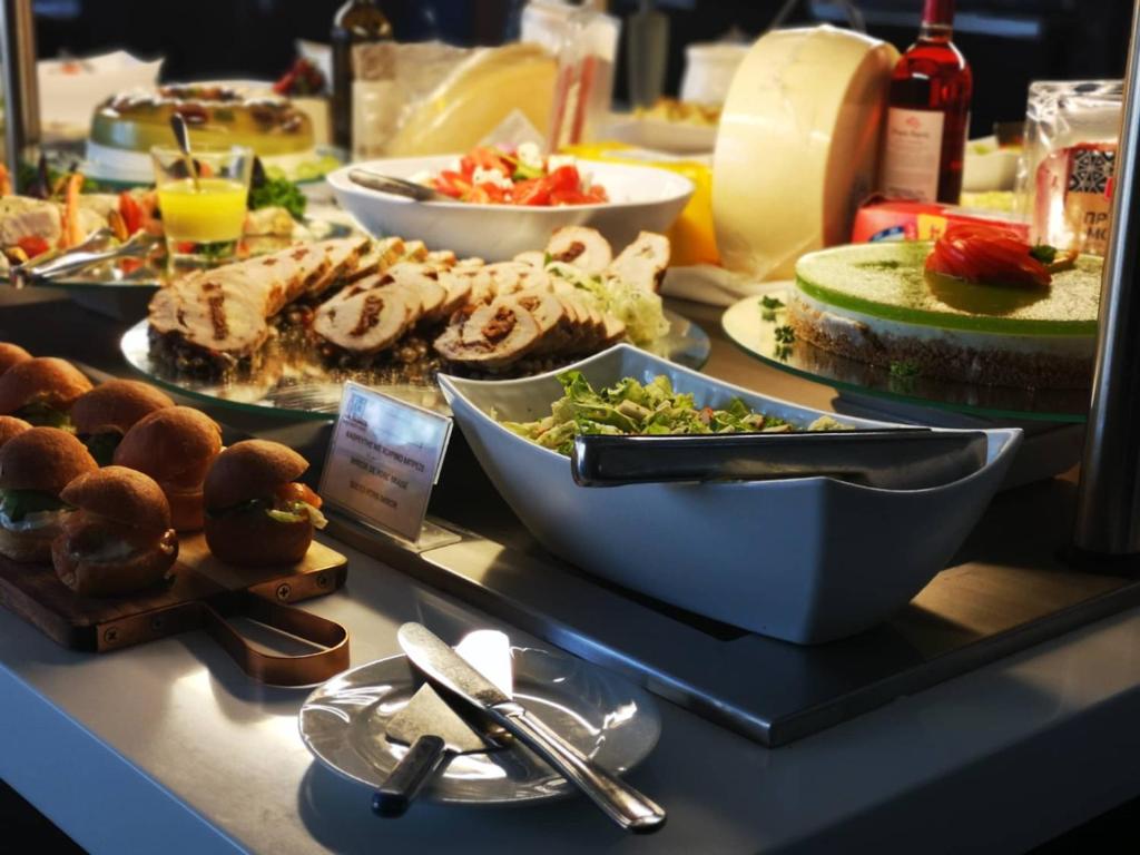 Brokastis vai bufete ar dažādiem ēdieniem, tostarp salātiem, gaļas izstrādājumiem un kūkām. Svaigi maizītes un dzērieni papildina ēdienkarti.