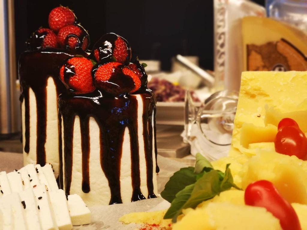 Saldā kūka ar zemenēm un šokolādes glazūru, blakus siera šķēles un tomāti. Ideāla uzkodu kombinācija svinībām.